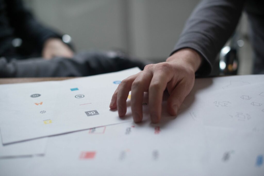 Une main examine plusieurs propositions de logos imprimées sur des feuilles de papier