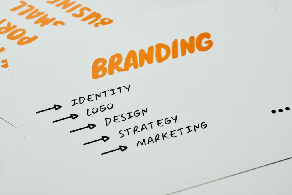 Feuille posée sur un bureau où sont écrits en orange et noir les mots branding, identité, design, stratégie et marketing