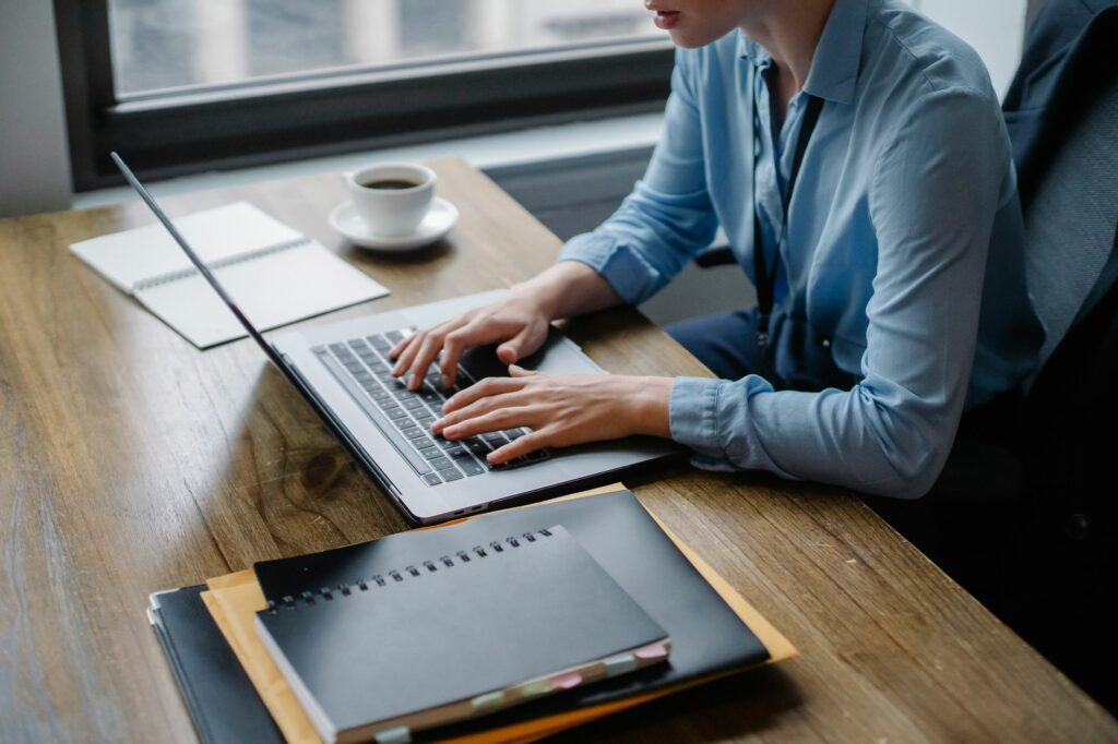 Dirigeant de PME au bureau, concentré devant son ordinateur portable, tasse de café et carnet de notes sur le bureau