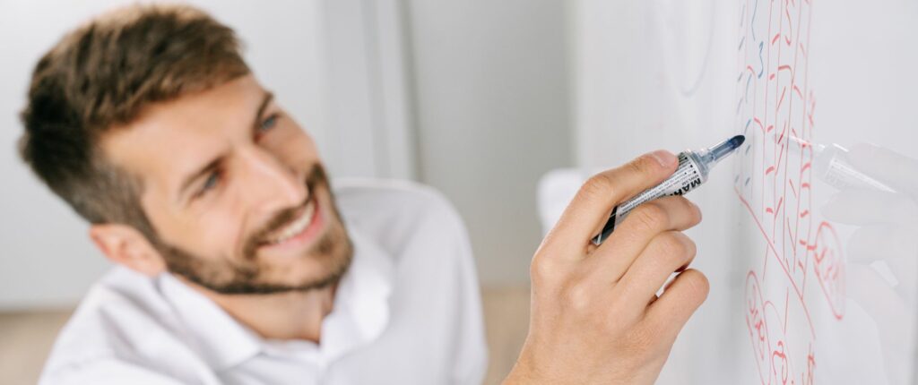 Un professionnel écrit ses idées sur un tableau blanc dans un bureau, en train de formuler sa proposition de valeur
