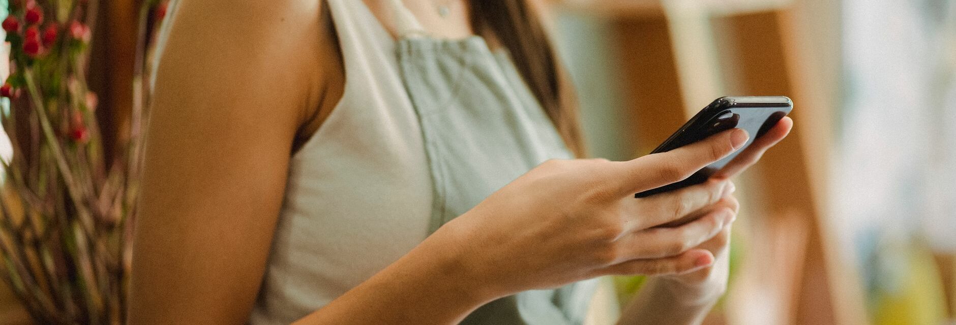 Une fleuriste en tablier consulte son smartphone dans sa boutique, pour gérer la page Facebook de son commerce local