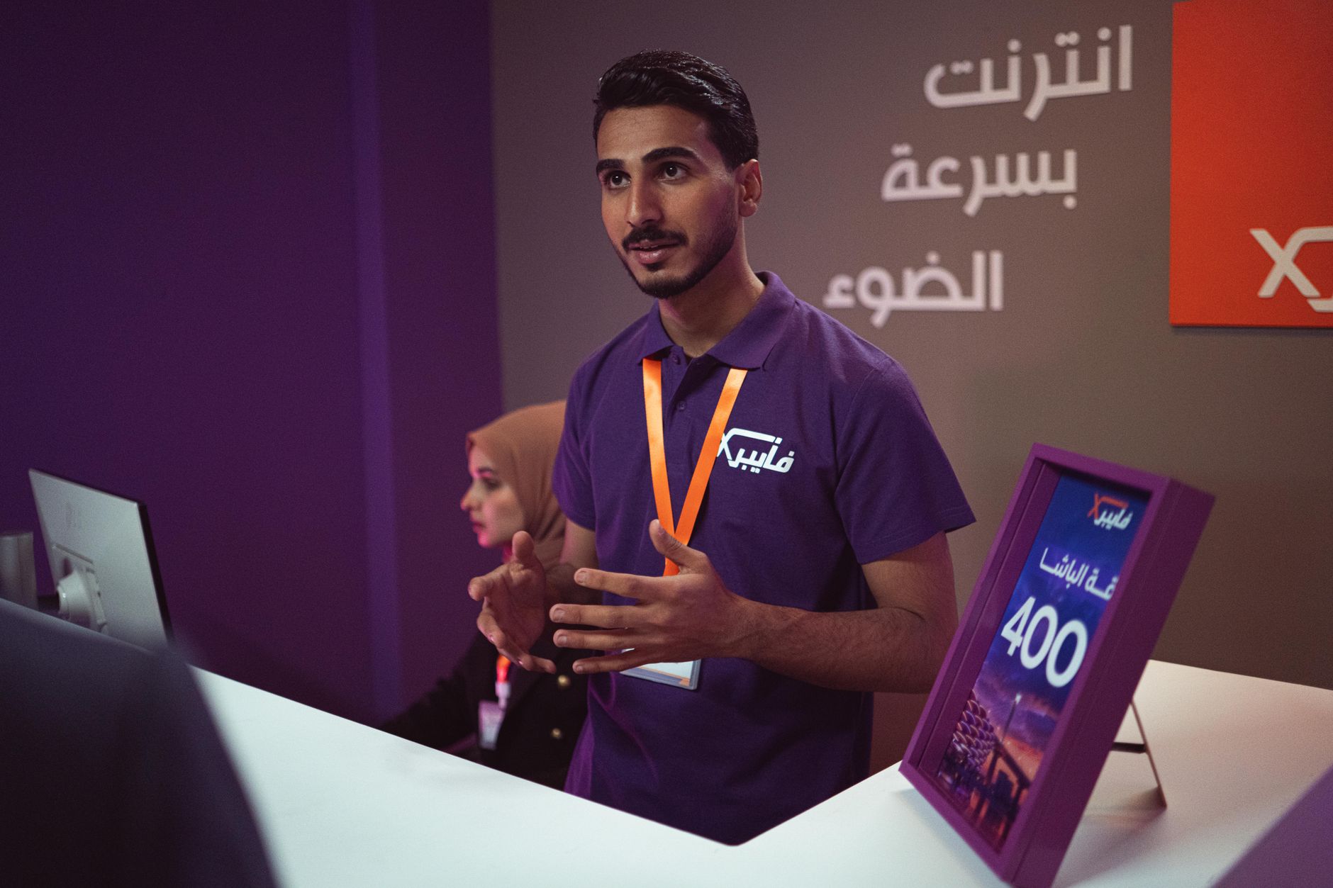 Homme sur un stand de salon professionnel expliquant une offre à un visiteur