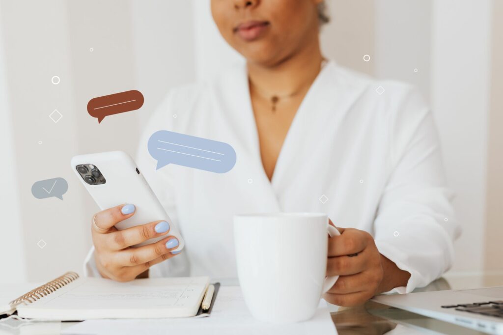 Gros plan sur une personne qui consulte son smartphone en tenant une tasse de café