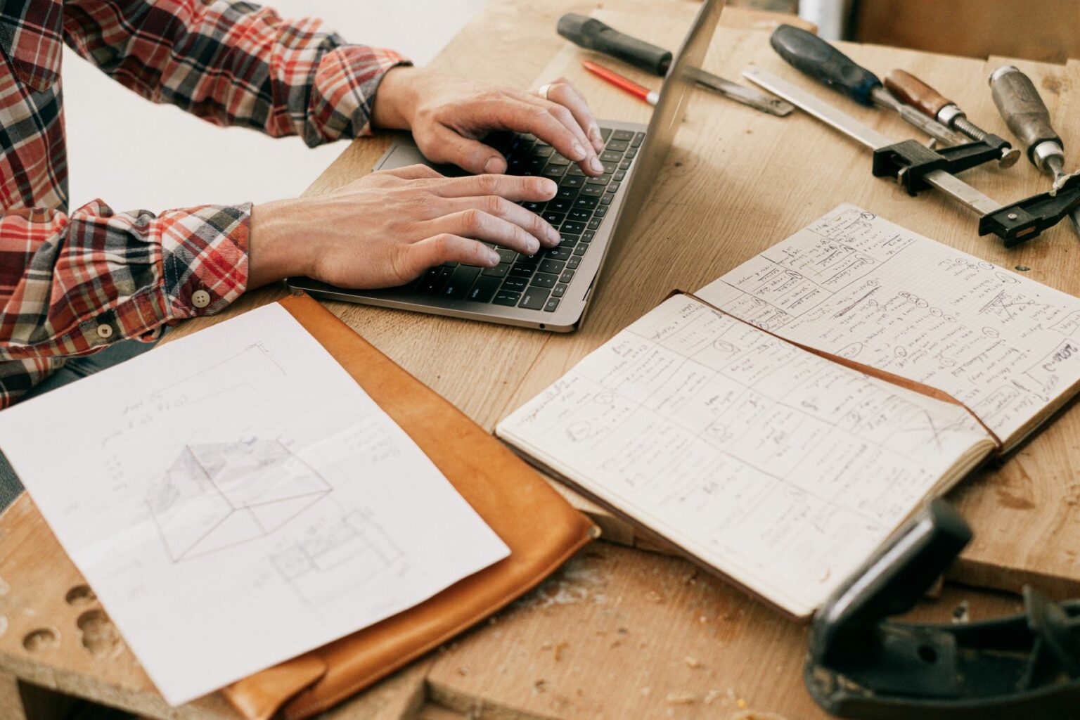 Un artisan menuisier utilise un ordinateur portable dans son atelier pour préparer son projet