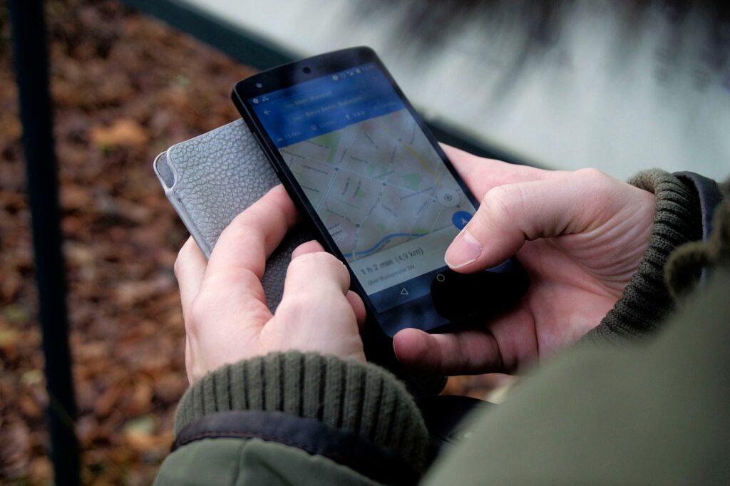 Gros plan de mains tenant un smartphone qui affiche une application de cartographie pour se repérer