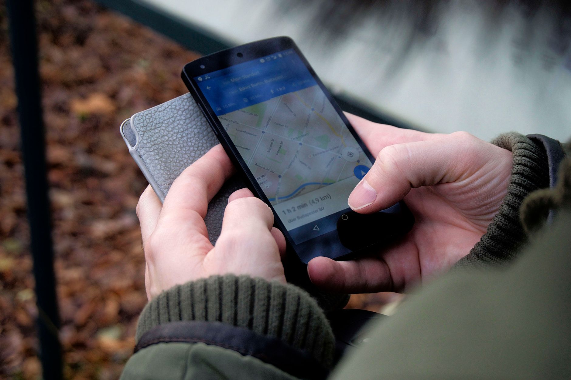Gros plan de mains tenant un smartphone qui affiche une application de cartographie pour se repérer